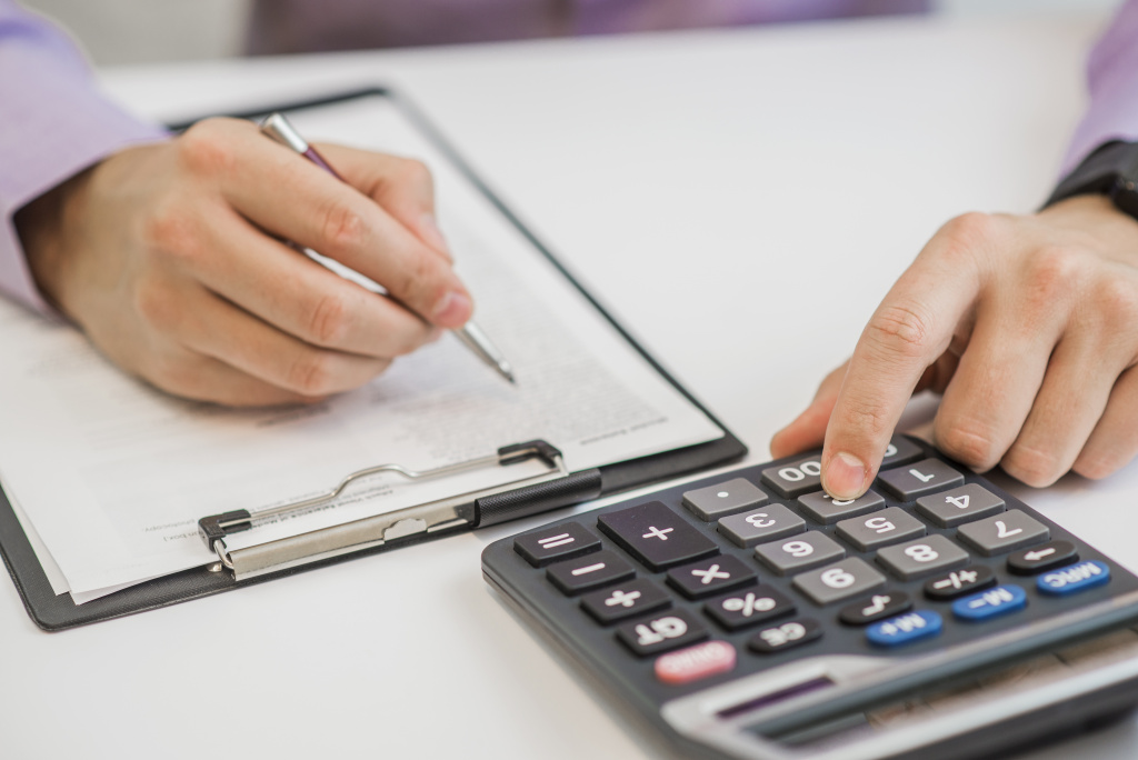 close-up-businessman-calculating-invoices-using-calculator.jpg